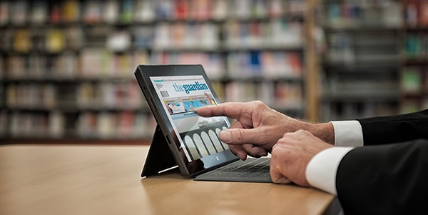 Foto av ein som nyttar lesebrett foran bibliotekhyller, illustrasjon for at systemet er nede