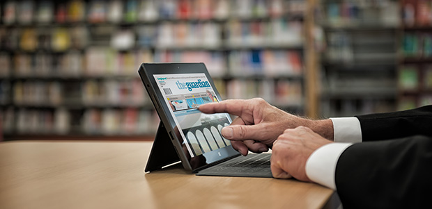 Foto av ein som nyttar lesebrett foran bibliotekhyller, illustrasjon for at systemet er nede